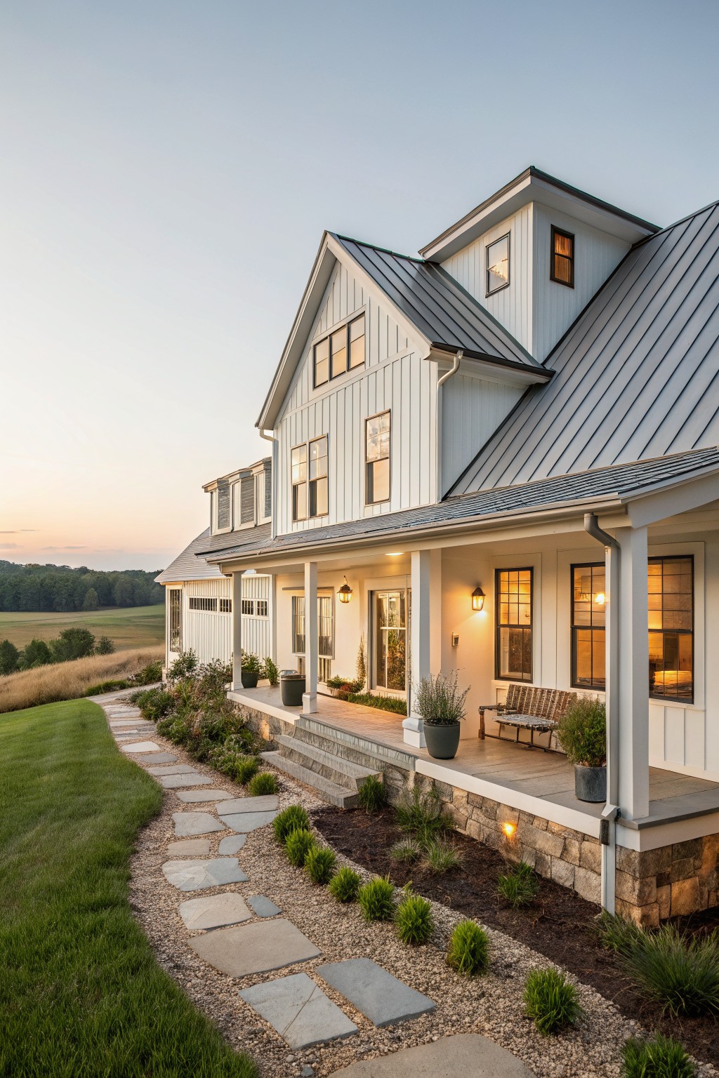 A white two-story farmhouse with a dark metal roof, front porch, and stone foundation at dusk.