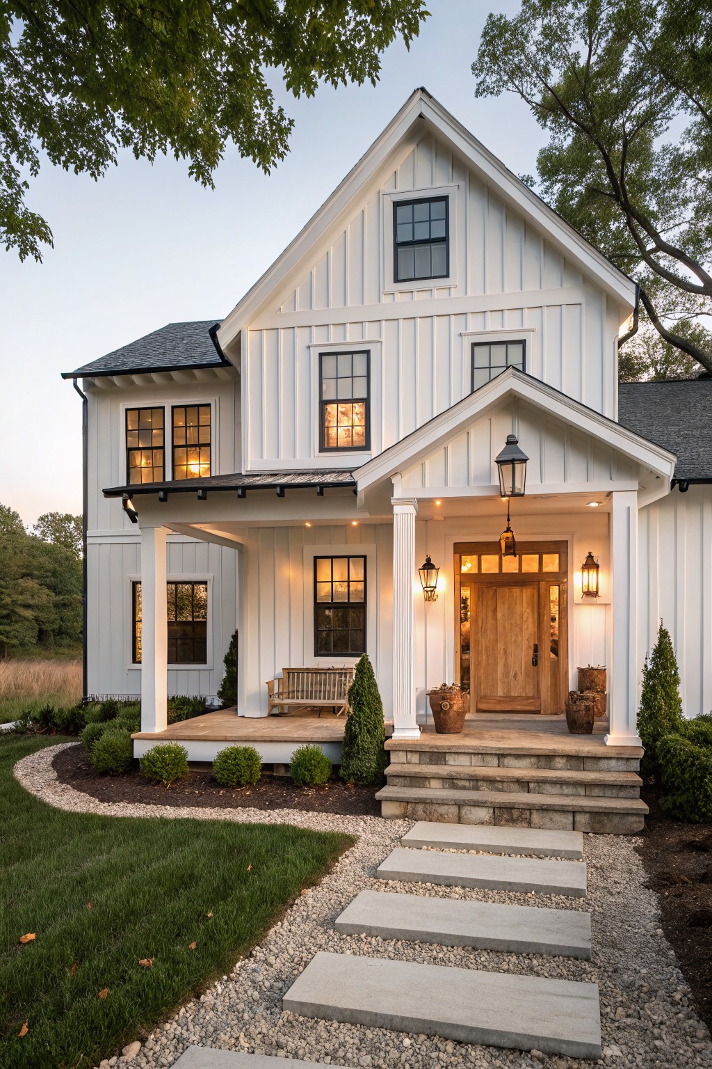 A white two-story farmhouse with a gabled front porch supported by white columns, stone steps, and a wooden front door.