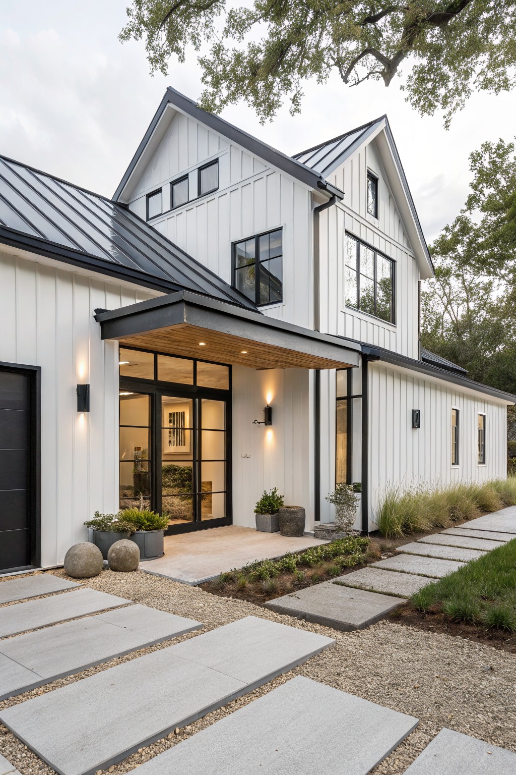 White farmhouse exterior with black metal roof, black trim around windows and doors, and a covered entry with wood ceiling and large glass doors.