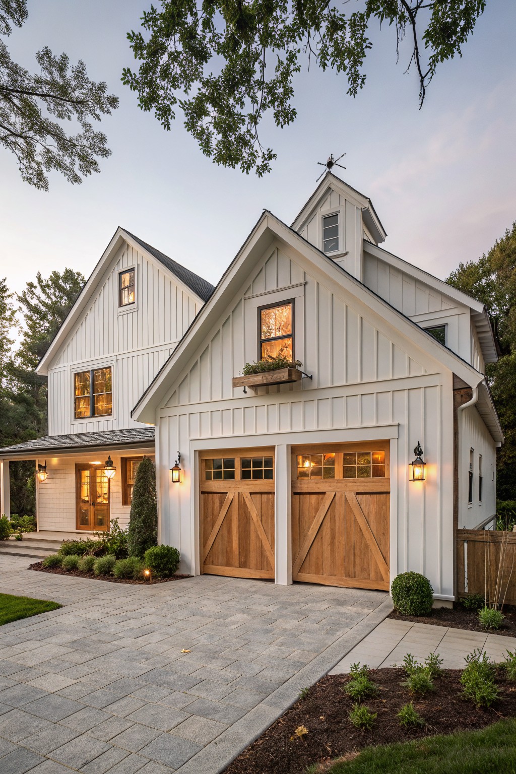 A white board and batten farmhouse exterior with wooden garage doors, a stone driveway, and a small cupola.