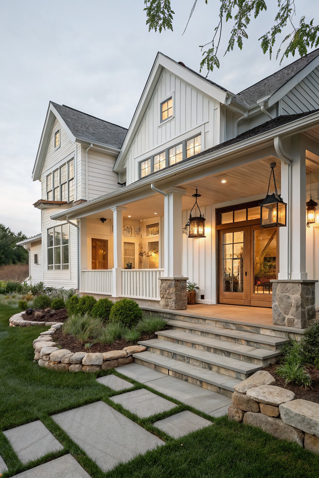 A white board and batten farmhouse with a covered porch, stone porch pillars, stone steps, and a double wooden front door.