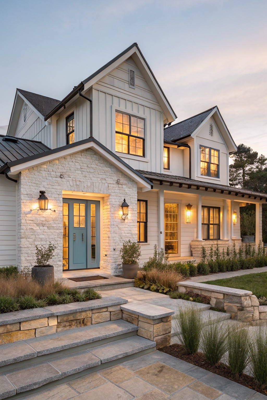 Modern white farmhouse with teal door, glowing windows, and stone steps at dusk