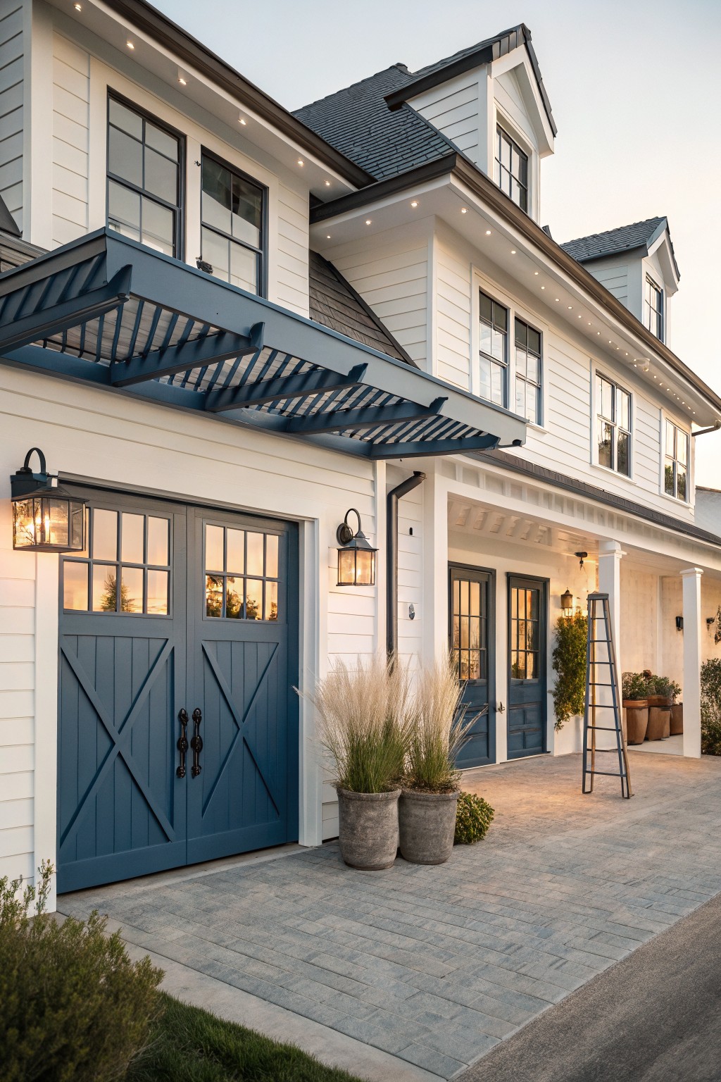 A white two-story coastal farmhouse with dark blue double garage doors, a blue pergola above them, and matching blue doors on the front porch.