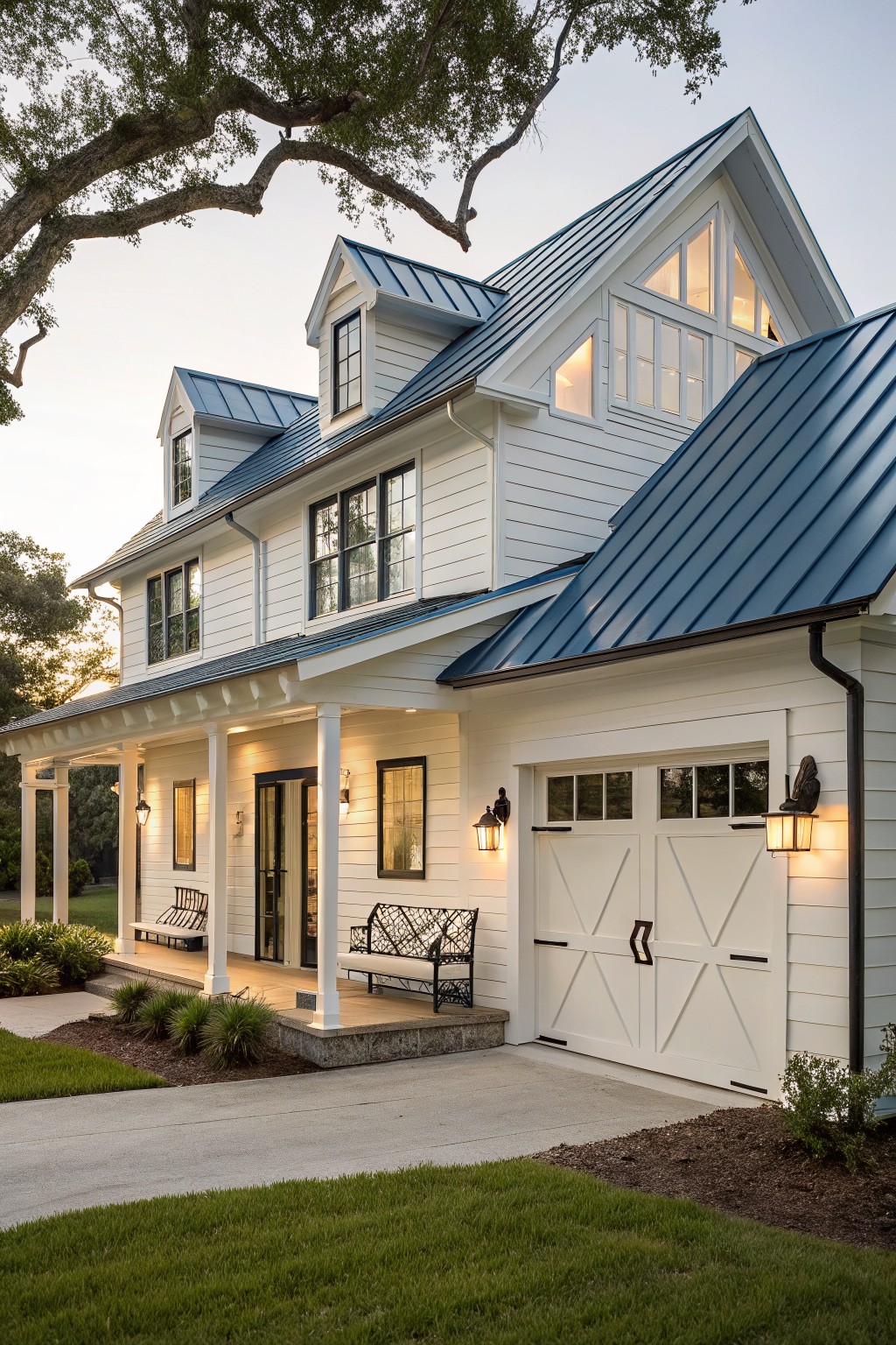 White two-story farmhouse with blue metal roofing, gabled dormers, white garage doors, and a covered front porch with benches.