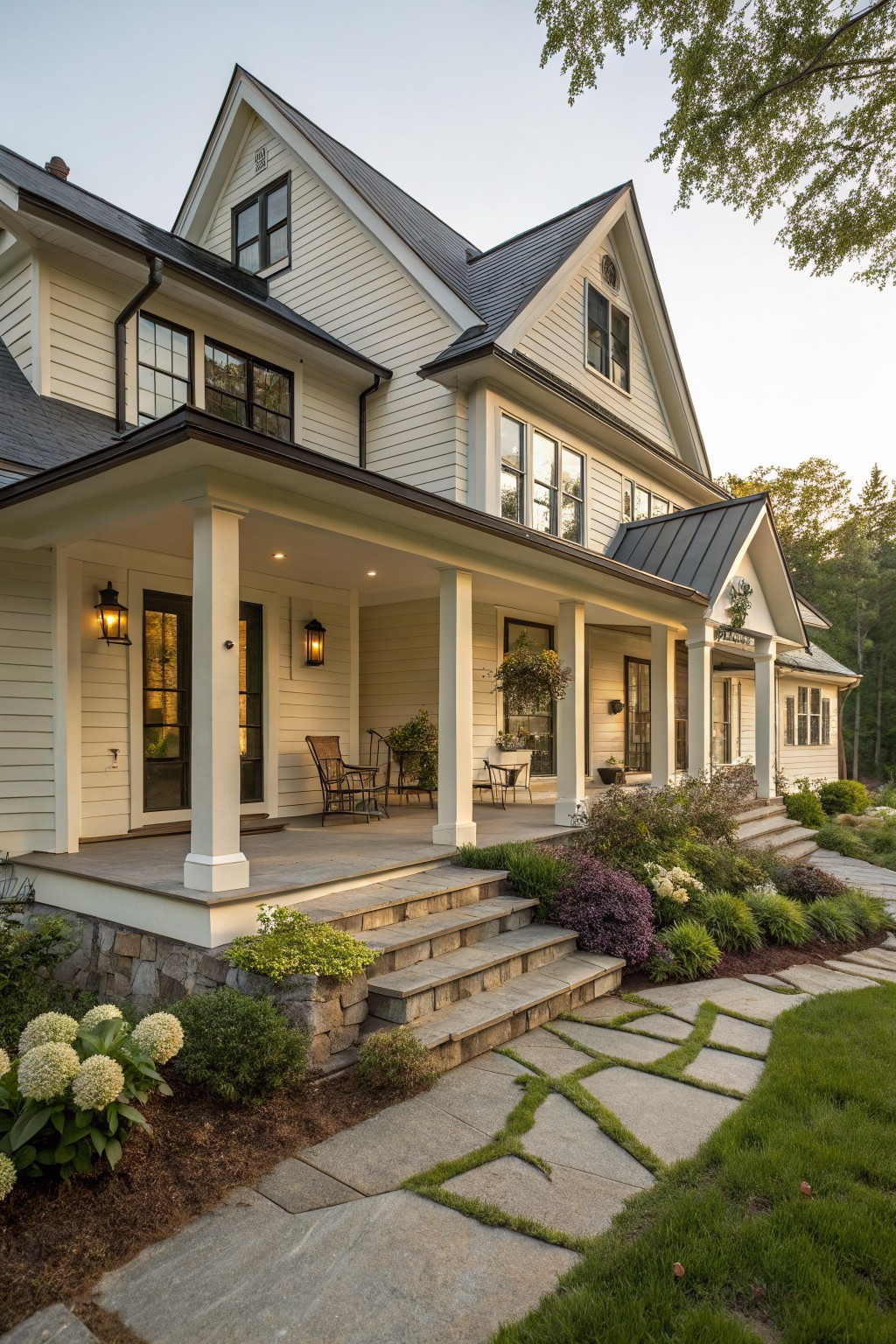 A two-story white house with a wide covered front porch supported by white columns, dark roofing, and stone steps leading up from a landscaped path.