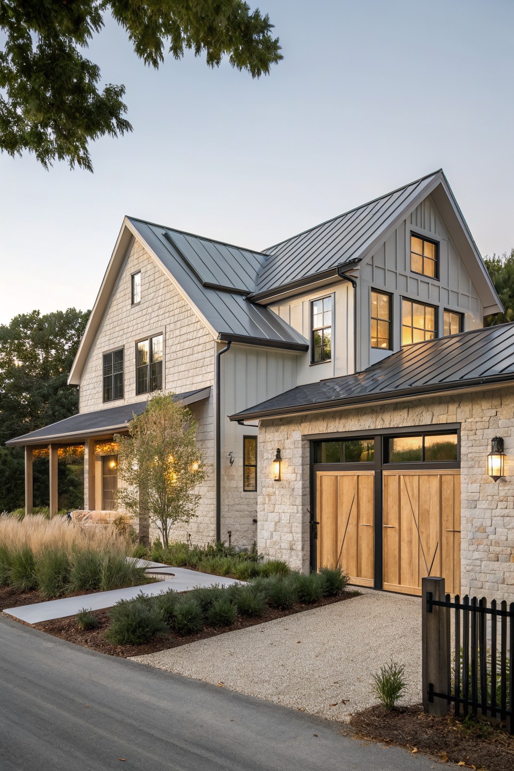 A contemporary farmhouse exterior with light siding on the main house, stone veneer on the garage wing, wooden garage doors, and a metal roof.