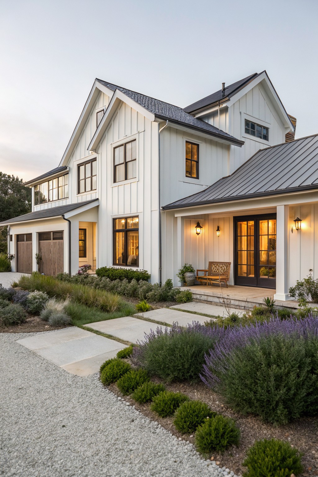 White modern farmhouse with black roof, porch, garage, and purple lavender garden.