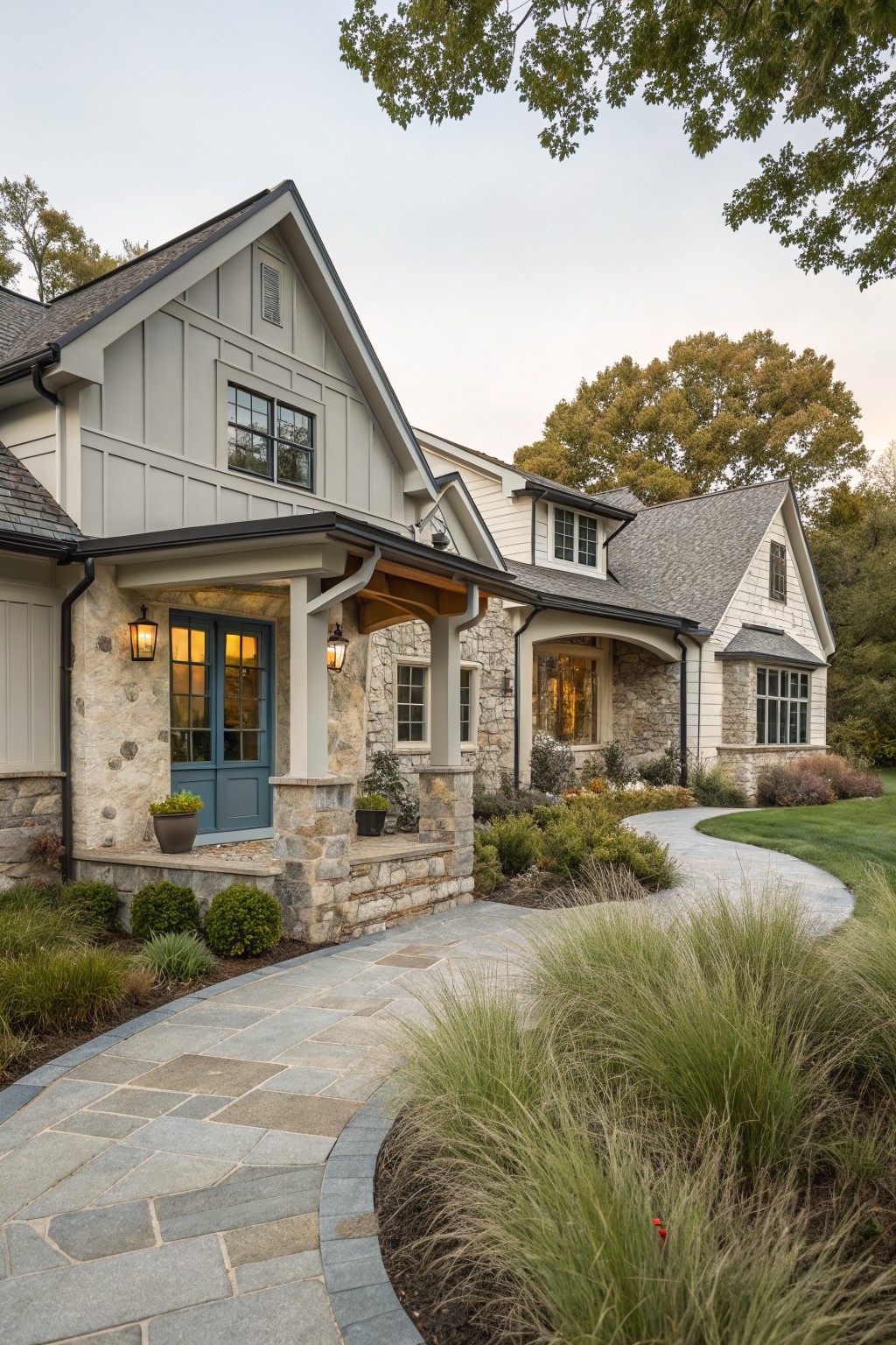 A farmhouse ranch exterior with light siding, stone on the lower walls and porch columns, a blue door, and a curved stone walkway.