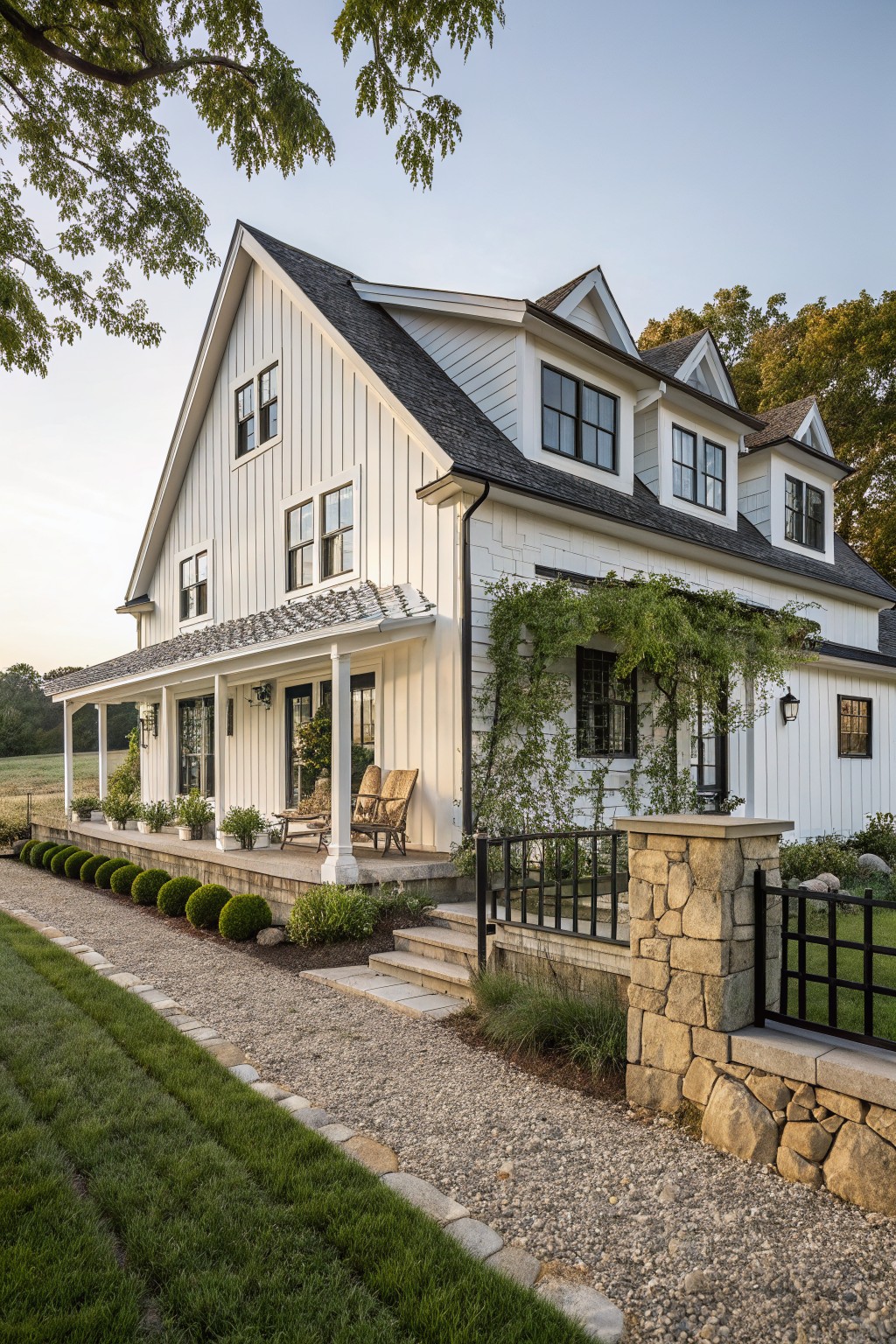 White board and batten farmhouse exterior with a covered porch, black windows, and stone entry pillars.