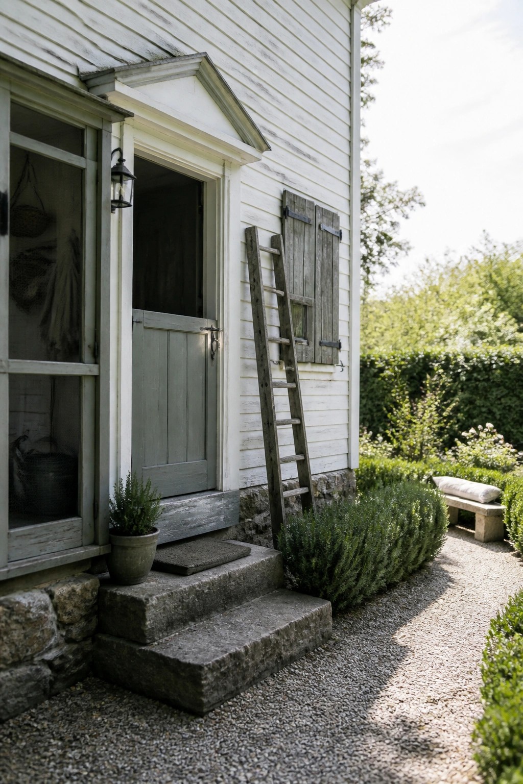 White wooden house entrance with gray door, stone steps, leaning ladder, and garden path