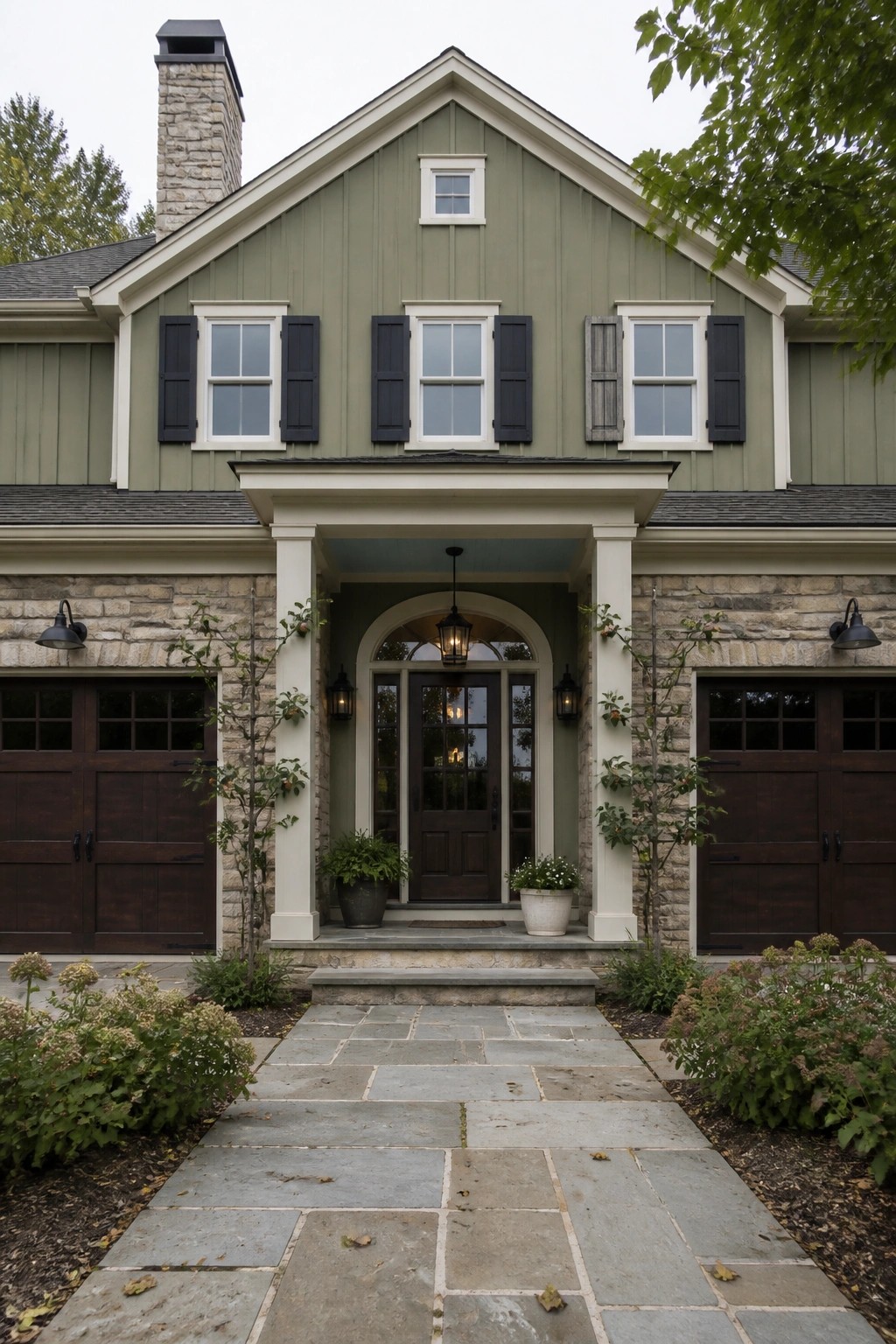 A stone farmhouse with soft sage green siding and white trim.