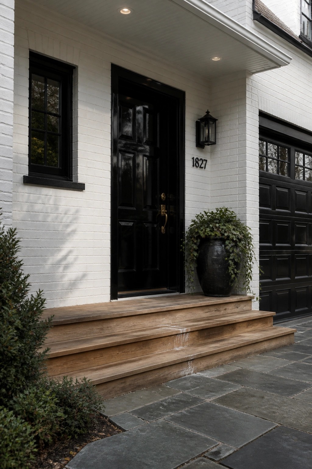 White brick exterior with black door and wooden steps.