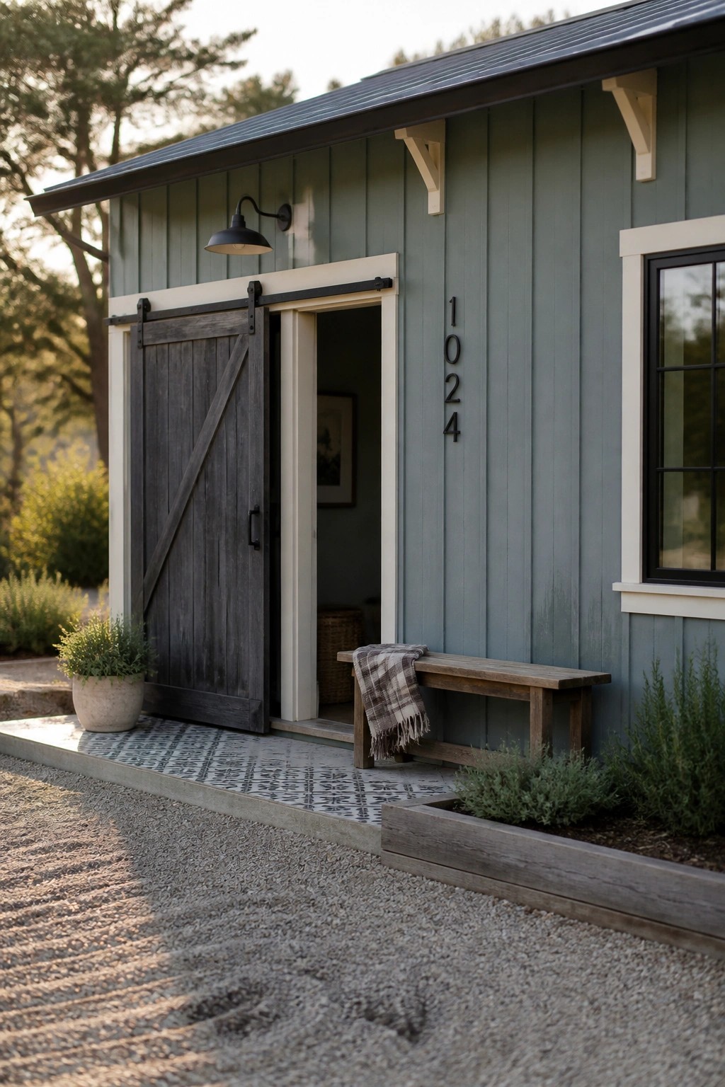 A farmhouse exterior shows soft sage gray siding with a dark sliding door.