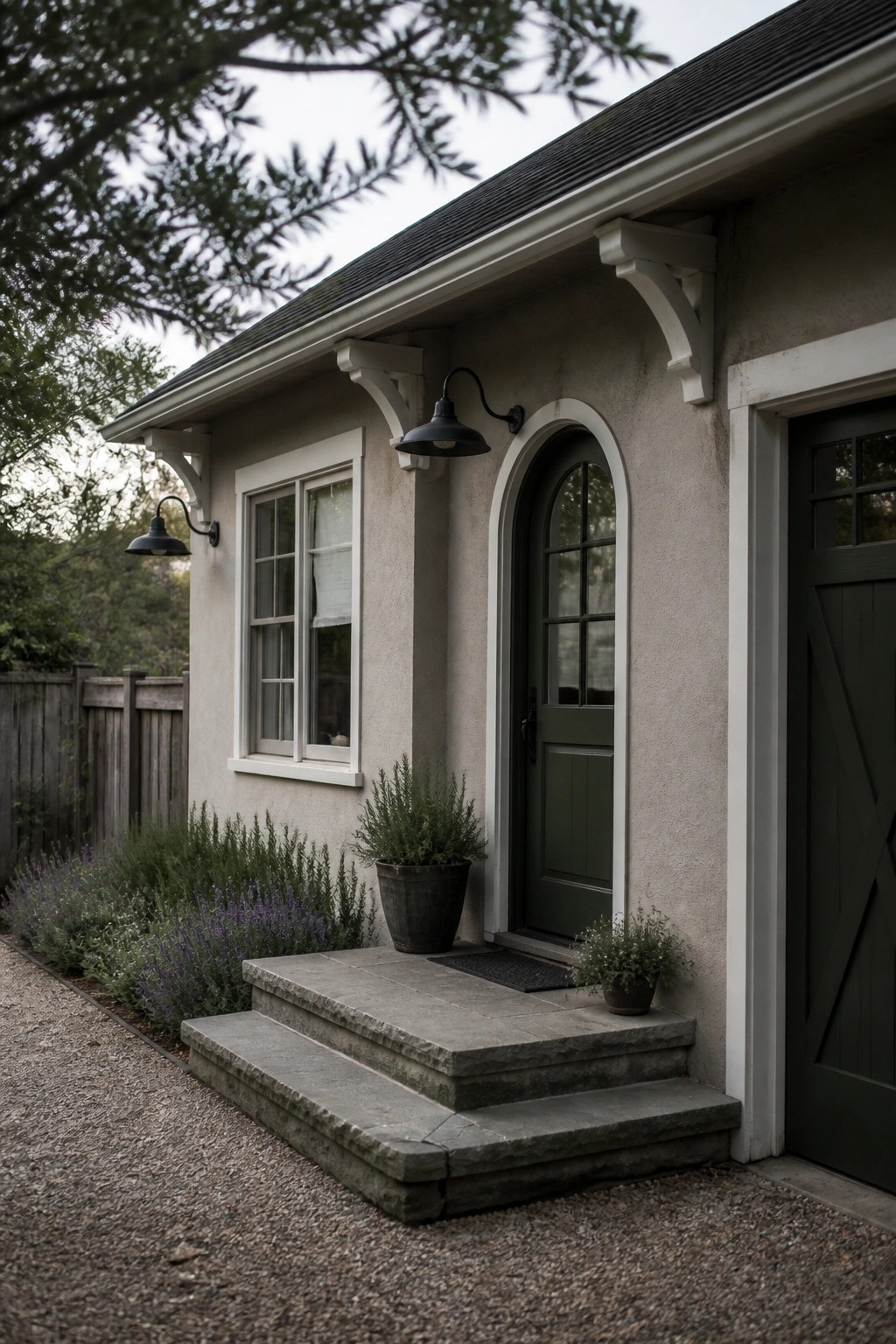 A modern farmhouse with soft greige siding and white trim around the arched door and window.
