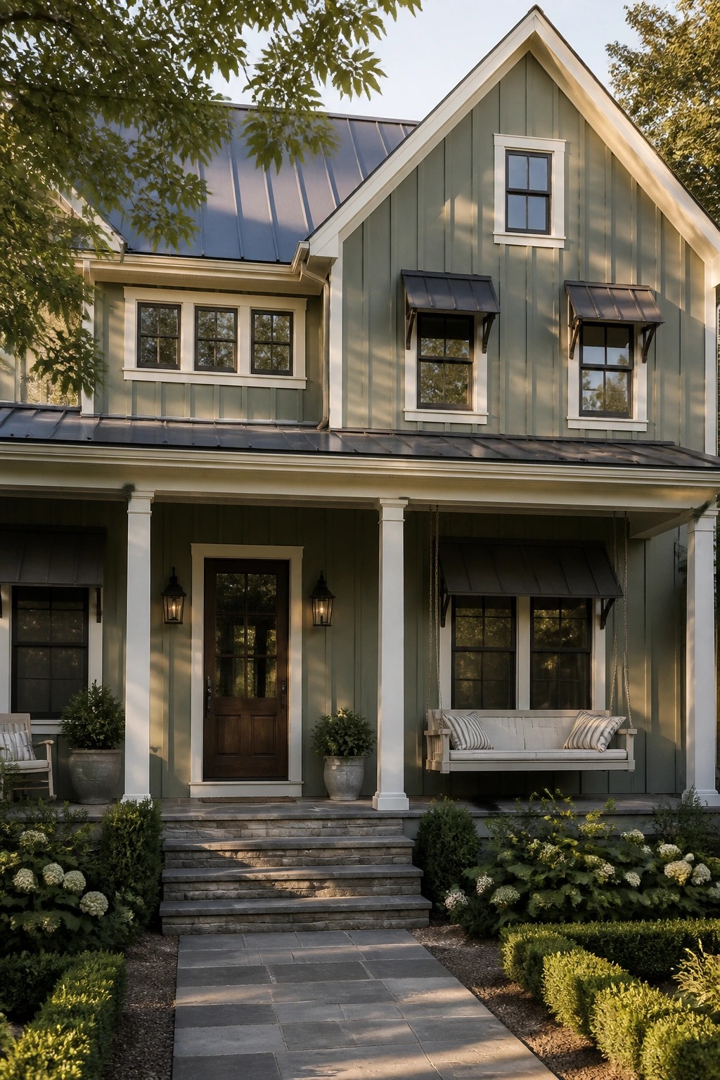 Green two-story house with porch swing, stone steps, and lush garden.