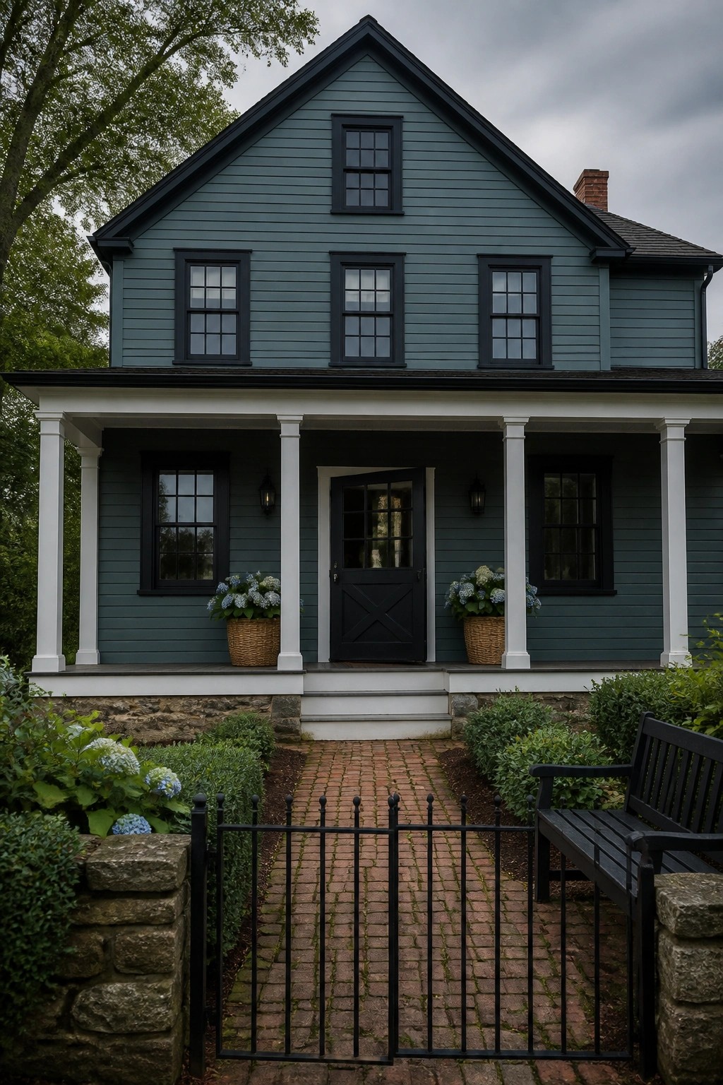 A modern farmhouse exterior painted in soft blue gray siding with black trim and white porch columns.