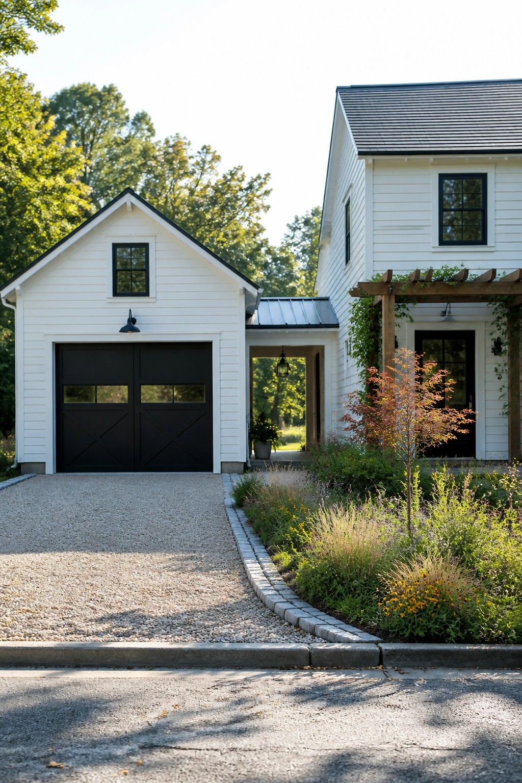 A white farmhouse with black garage doors, black window frames, and a matching white detached garage connected by a covered walkway, with a gravel driveway in front.
