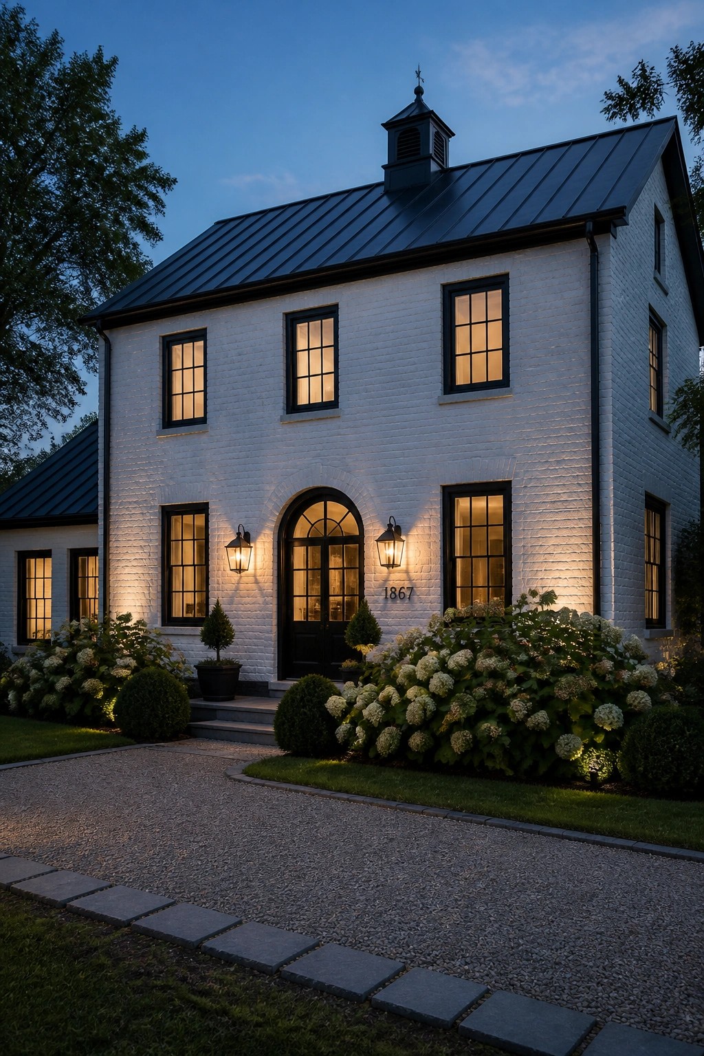 White painted brick exterior of a two-story farmhouse with black windows.