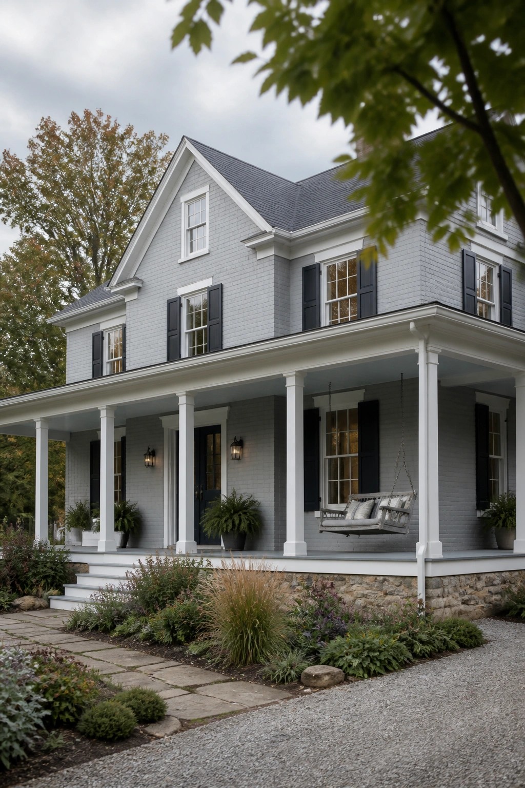 A two-story farmhouse with light gray painted brick and a white front porch.