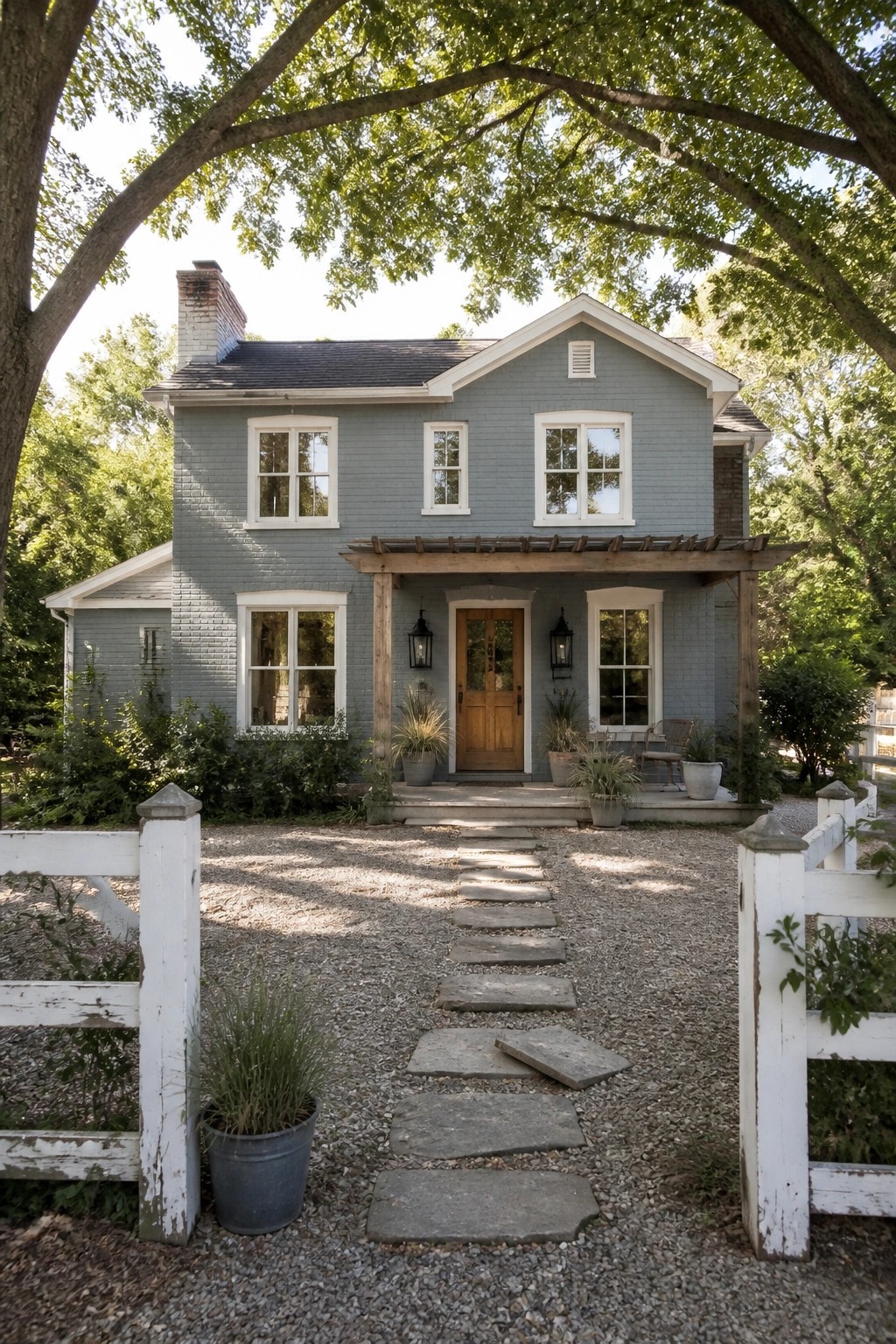 A two-story farmhouse with soft blue gray painted brick siding and a gravel path to the front door.