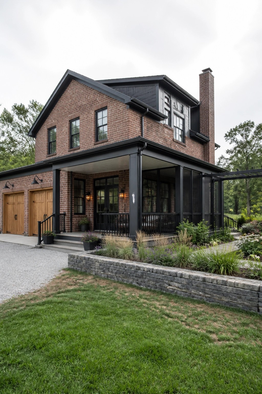 A two-story red brick house with black trim, a covered front porch, wooden garage doors, and a brick chimney, shown from the front with landscaping in the foreground.