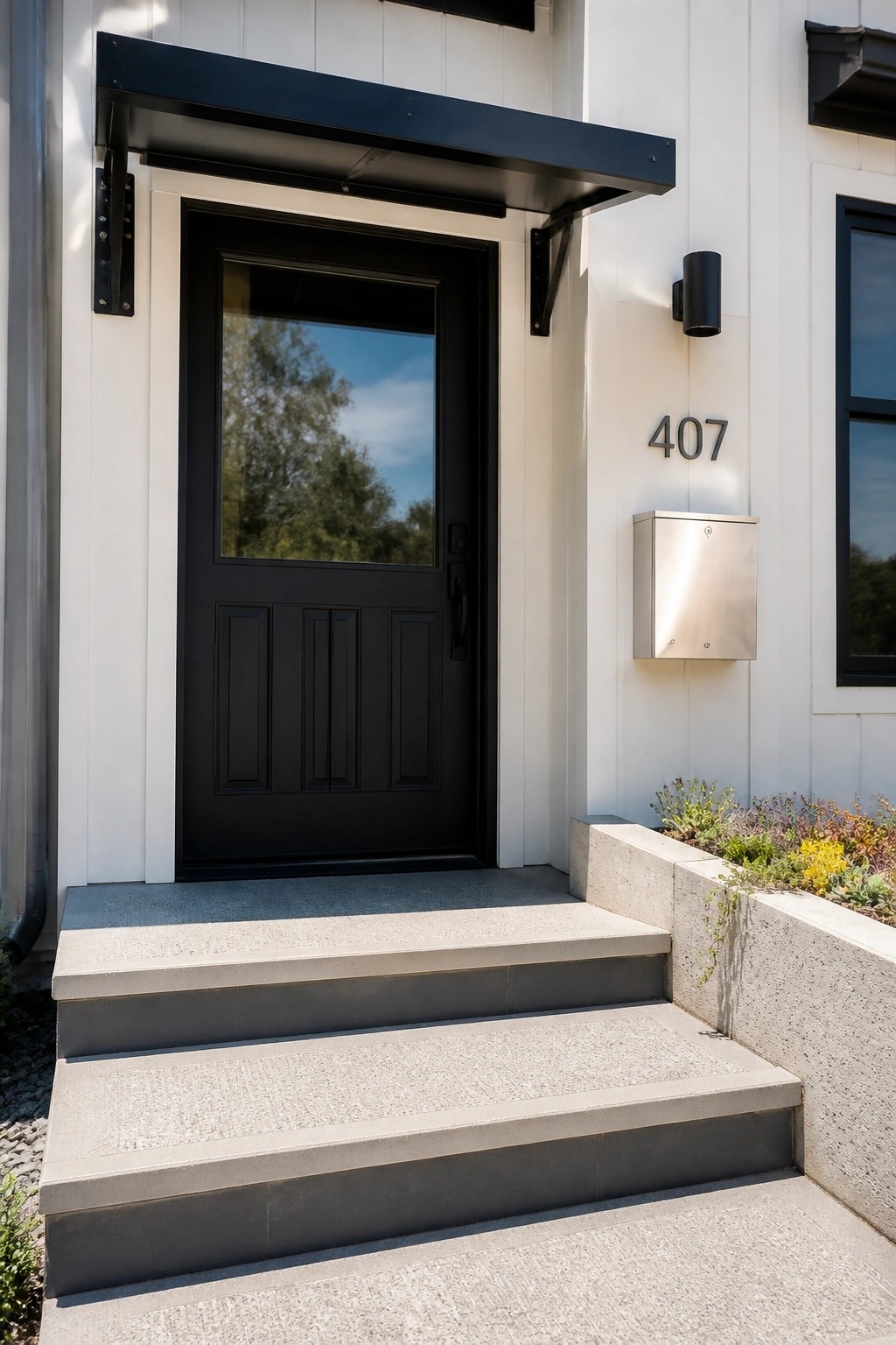 A black front door with a window panel and three lower sections, set in white siding with concrete steps, a metal mailbox, and a black wall sconce beside the door.