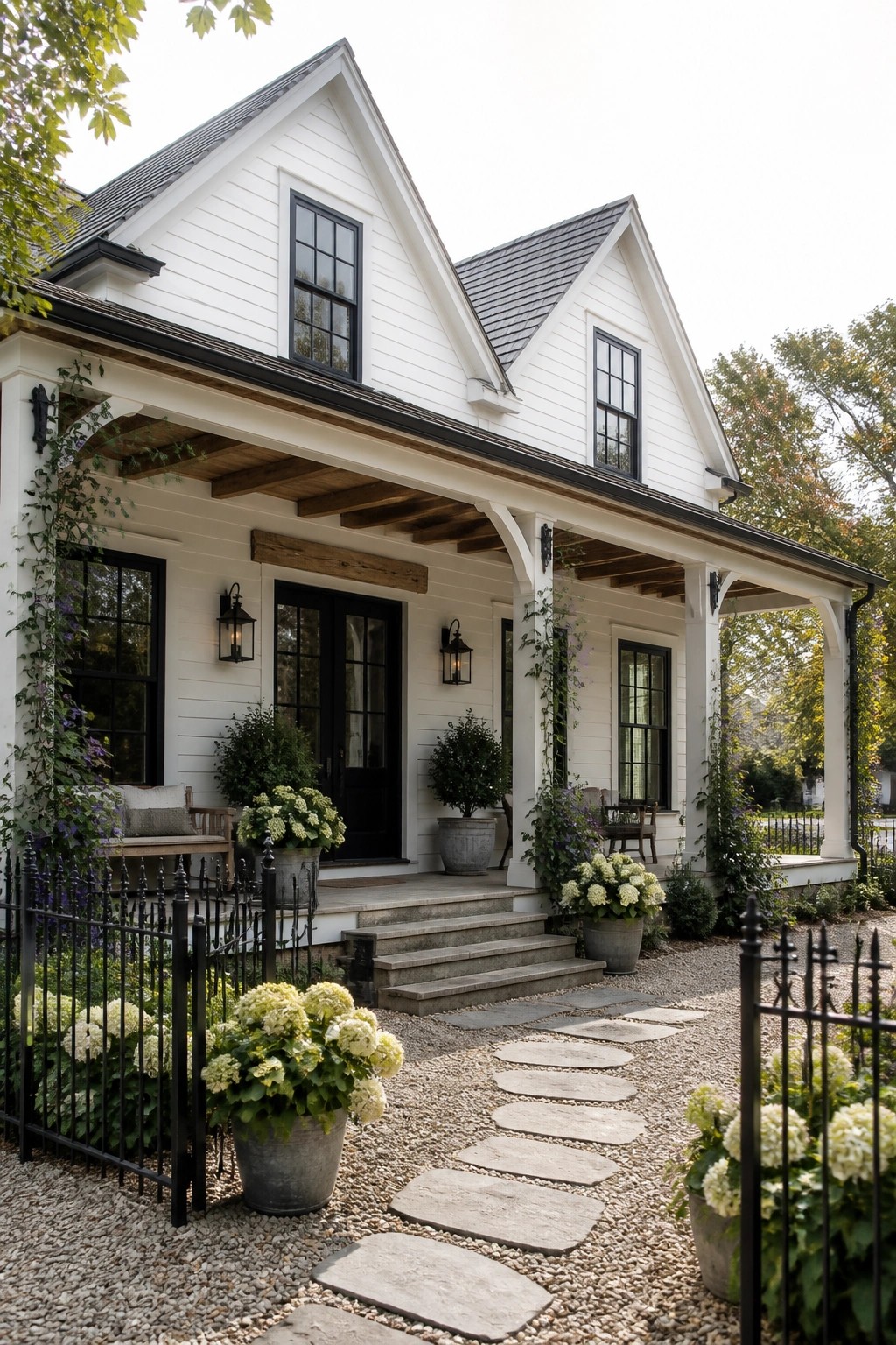 White cottage with black trim, porch, stone path, and blooming hydrangeas.