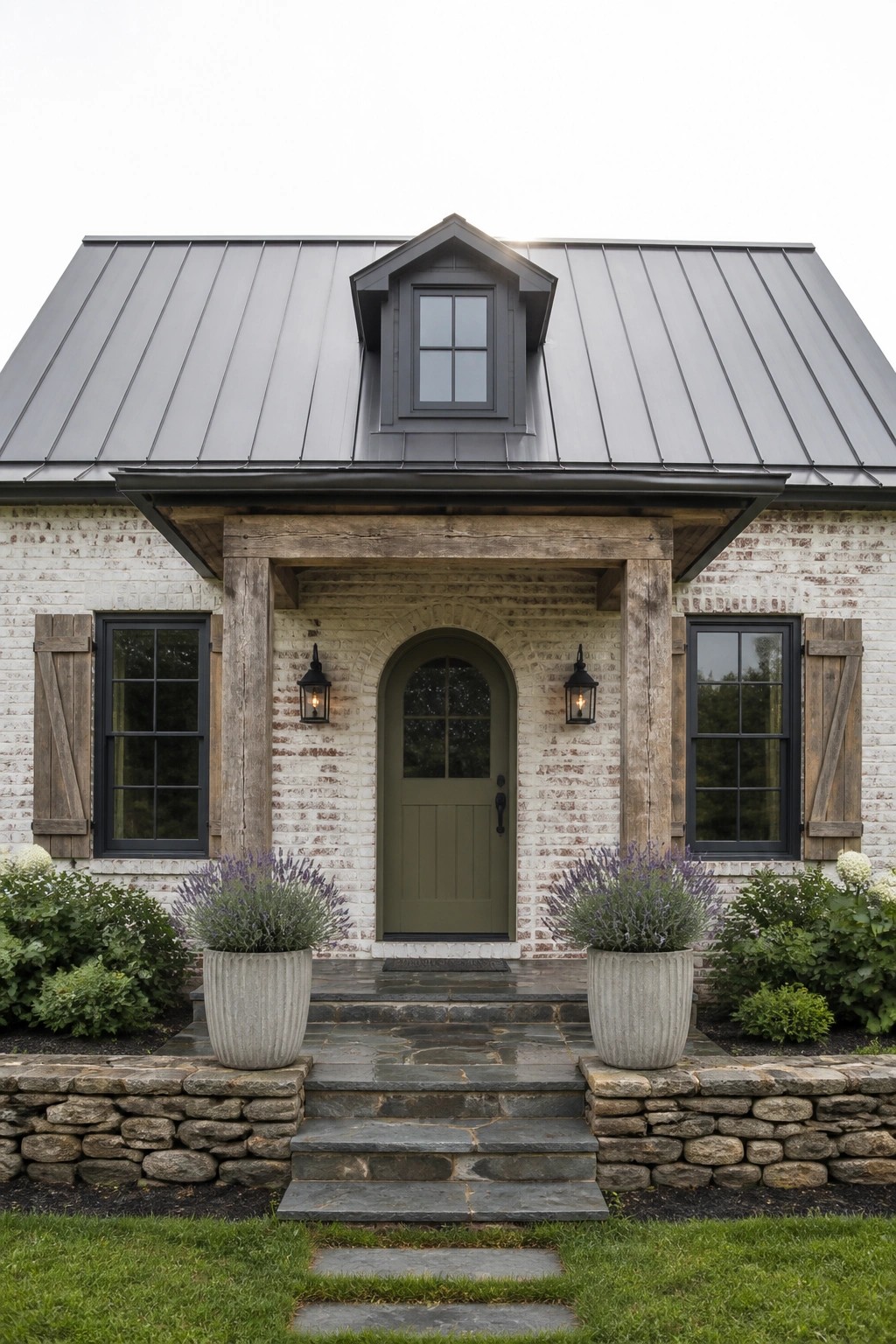 White brick house with green arched door, stone steps, and potted lavender.