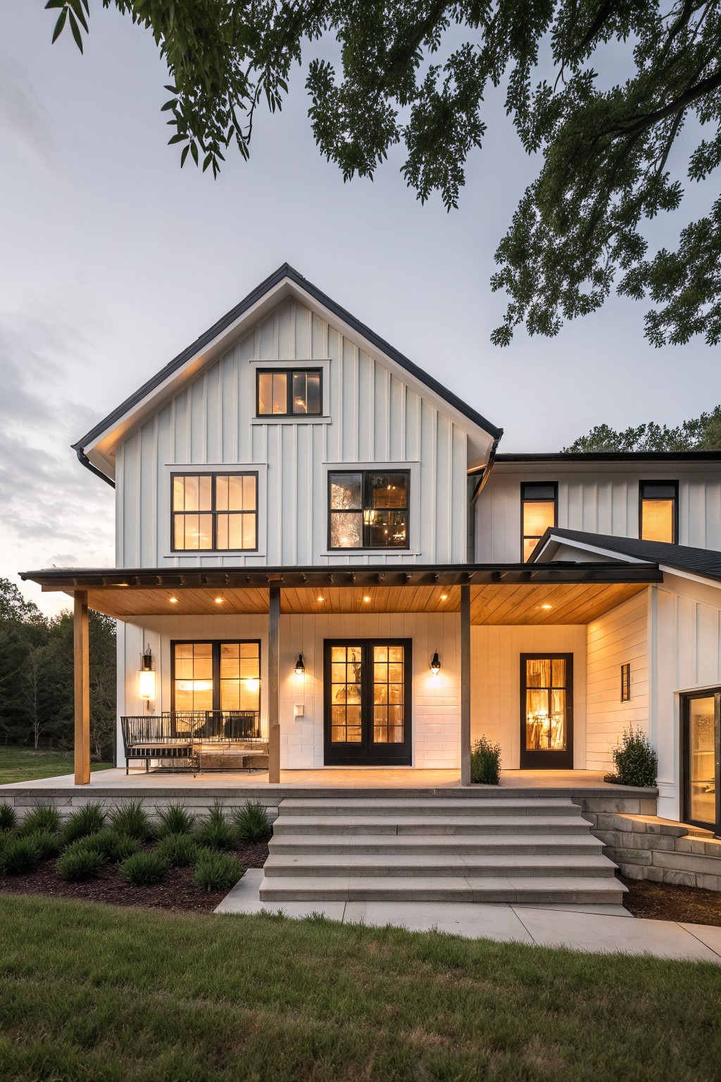 A two-story white farmhouse with vertical siding, a covered porch with wood ceiling and posts, black-framed windows and doors, and concrete steps leading to the entrance.