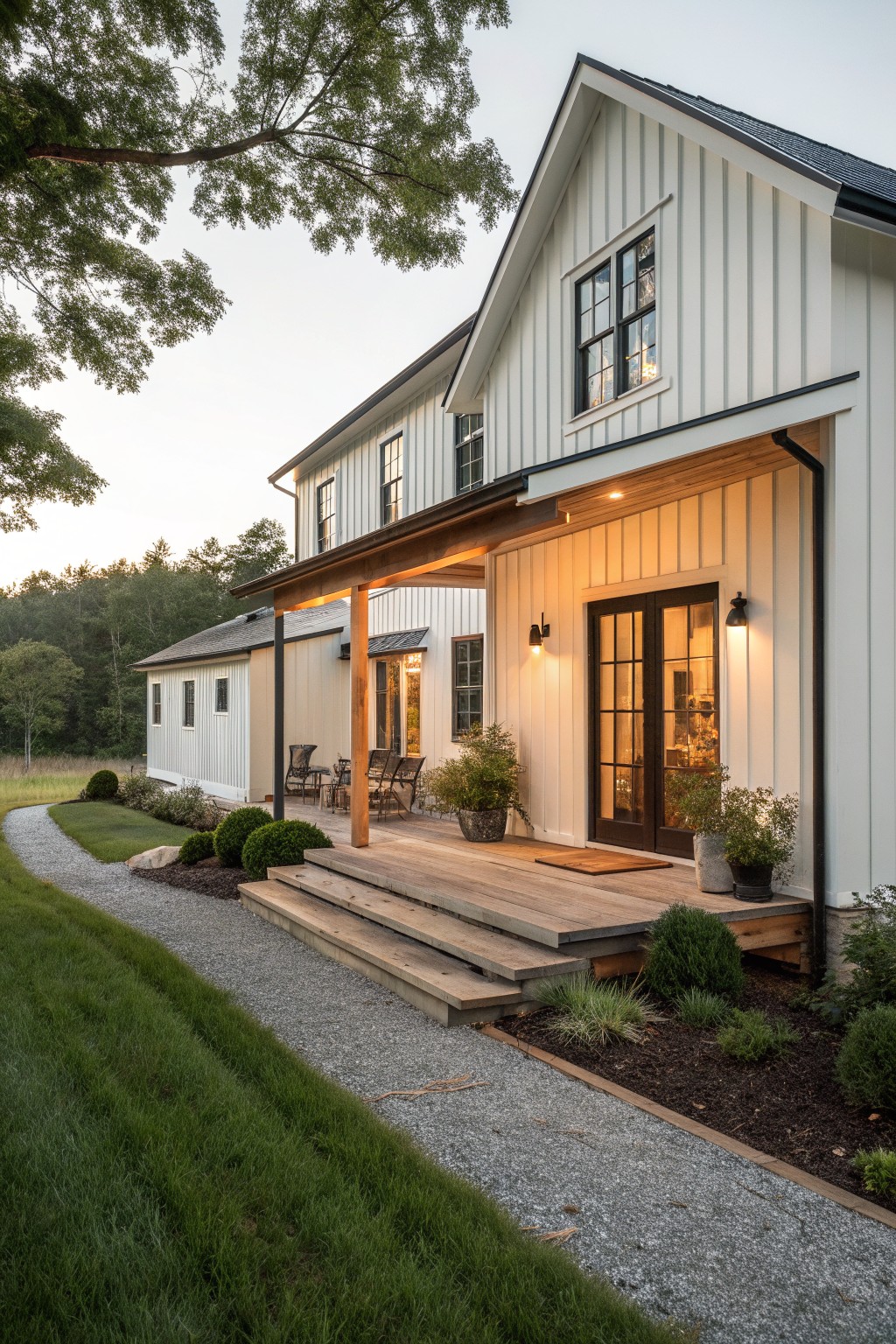 White two-story farmhouse with wooden porch, steps, and gravel pathway at dusk