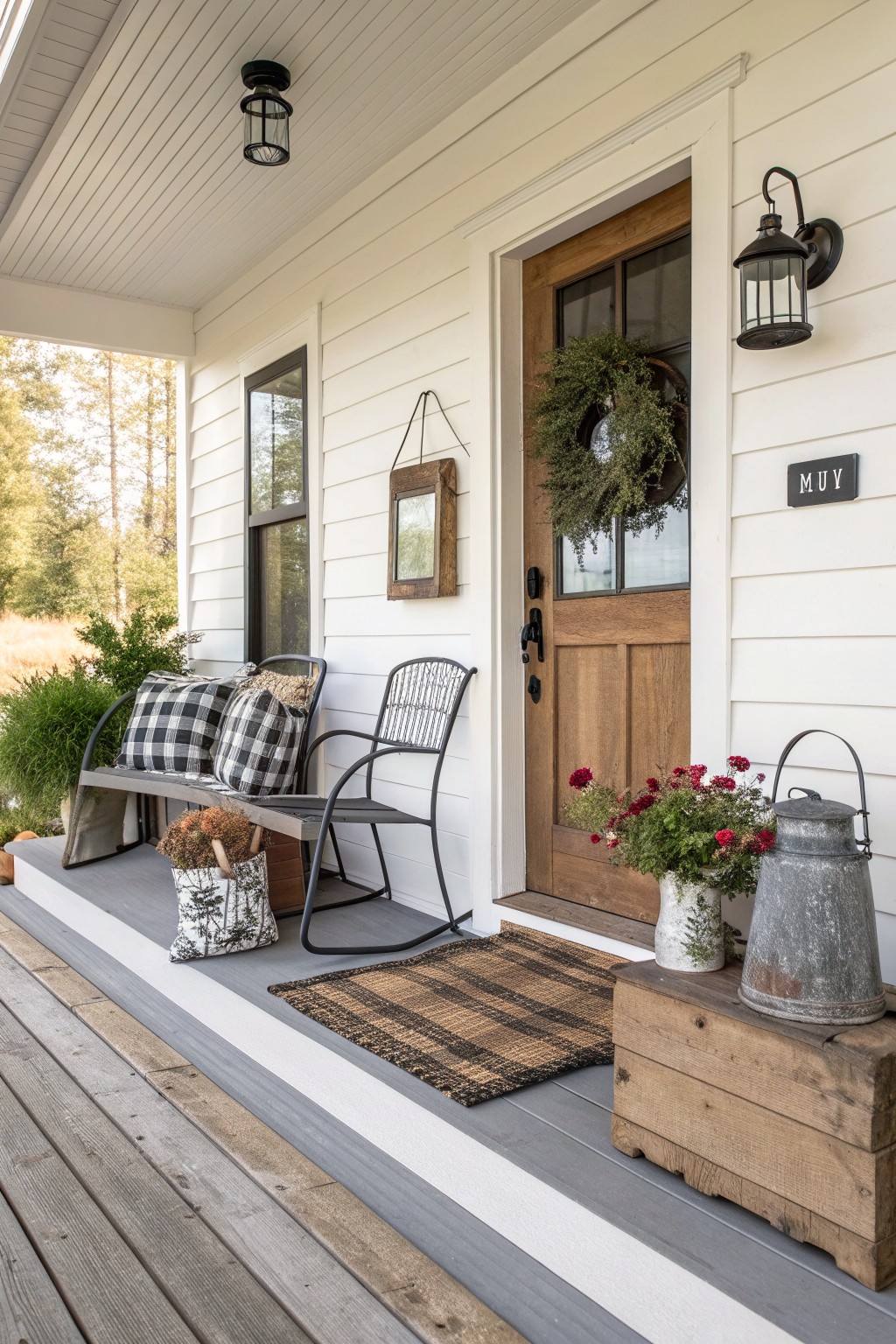 Cozy white farmhouse porch with plaid chairs, wooden door, wreath, and rustic floral decor.