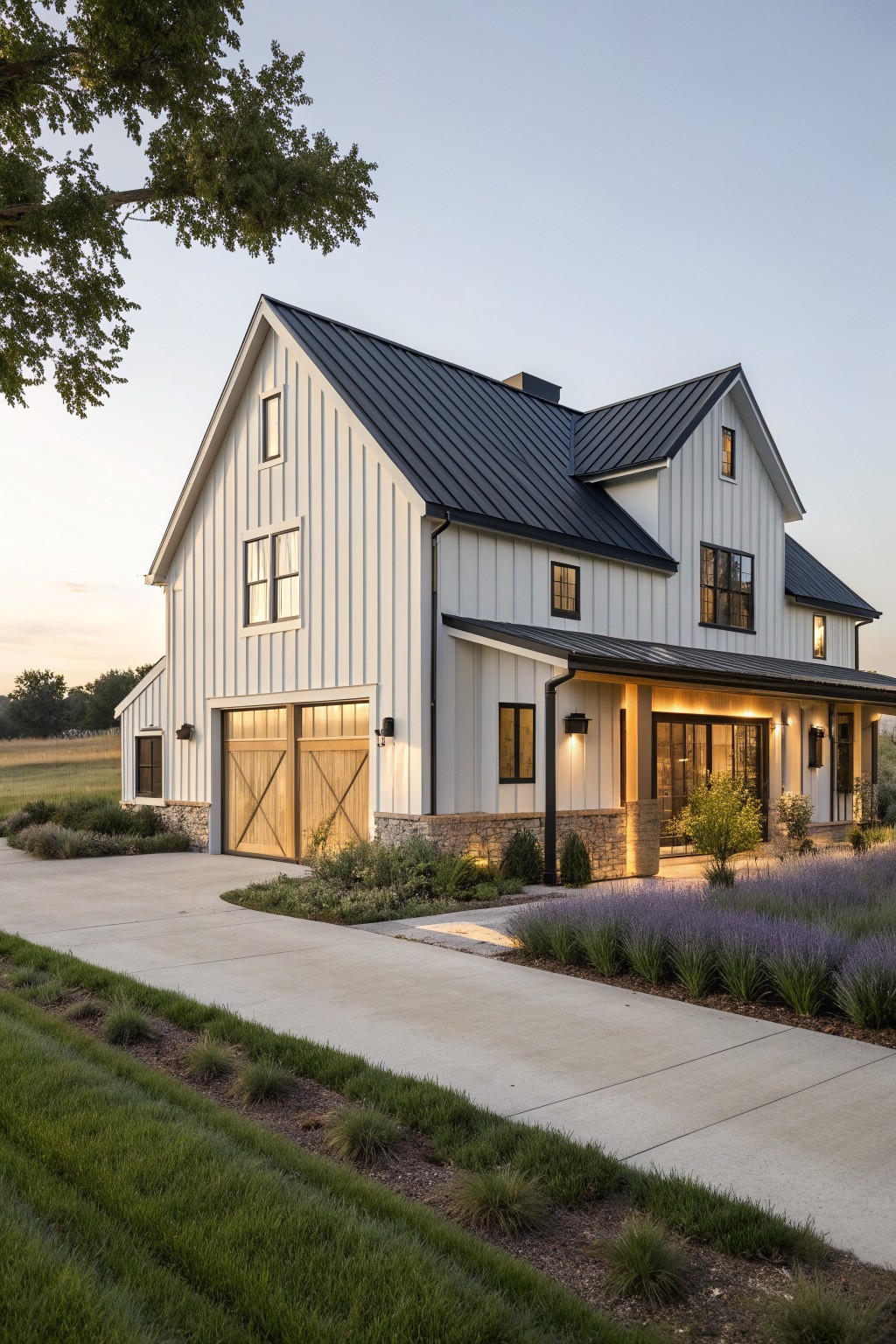 Modern white farmhouse with black roof, wooden garage doors, and lavender-lined driveway at dusk