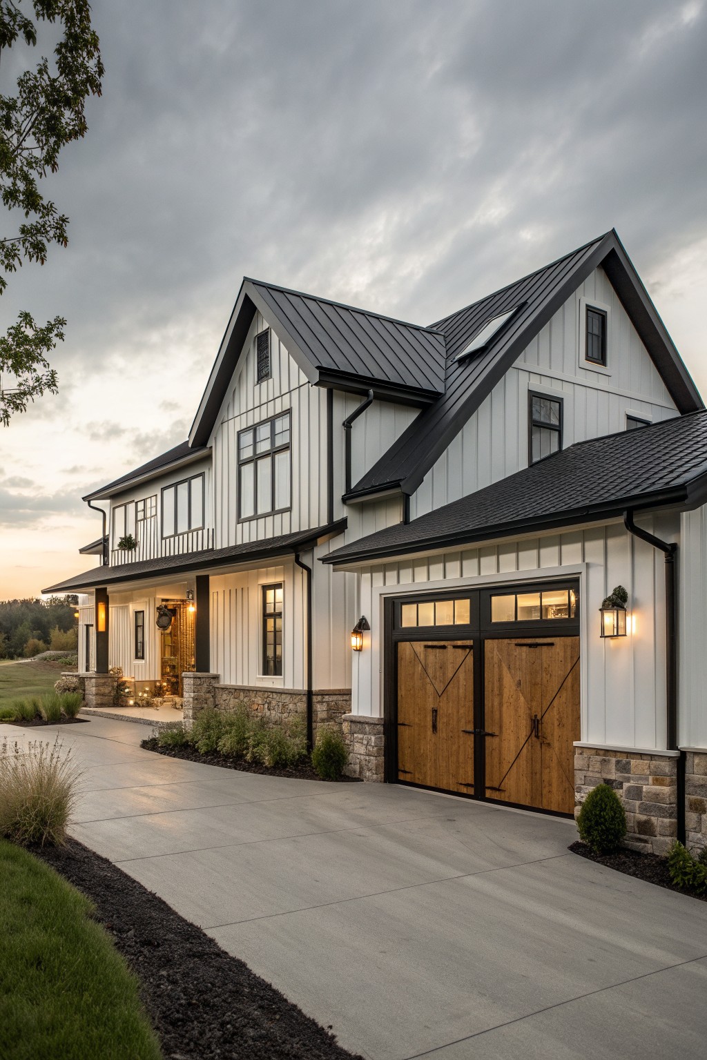 A two-story modern farmhouse exterior featuring white vertical siding, black metal roofing, a stone foundation, and wooden garage doors with black frames.