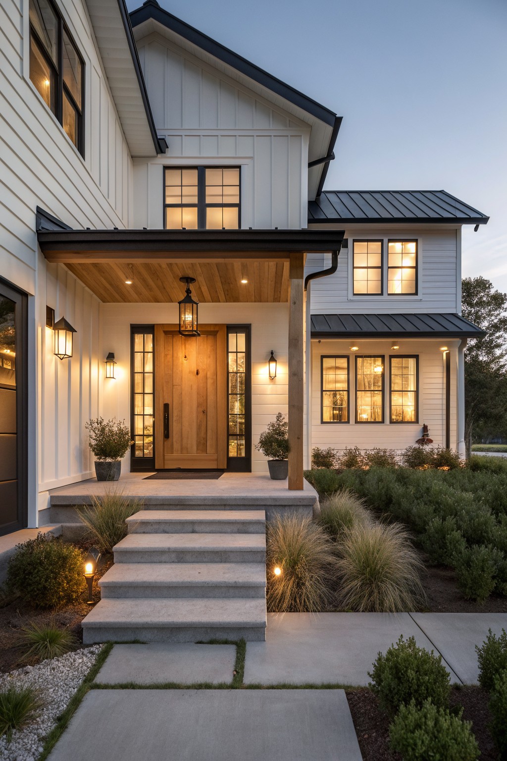 Front view of a white modern farmhouse with black trim, a covered porch with wood ceiling, a wooden front door flanked by glass sidelights, and concrete steps.