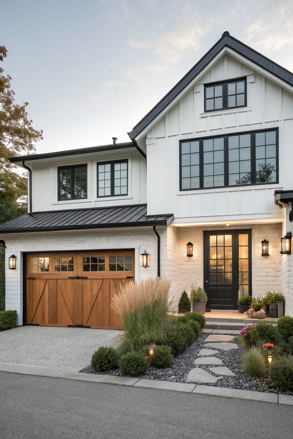 Modern white house with black trim, wooden garage door, and stone pathway garden