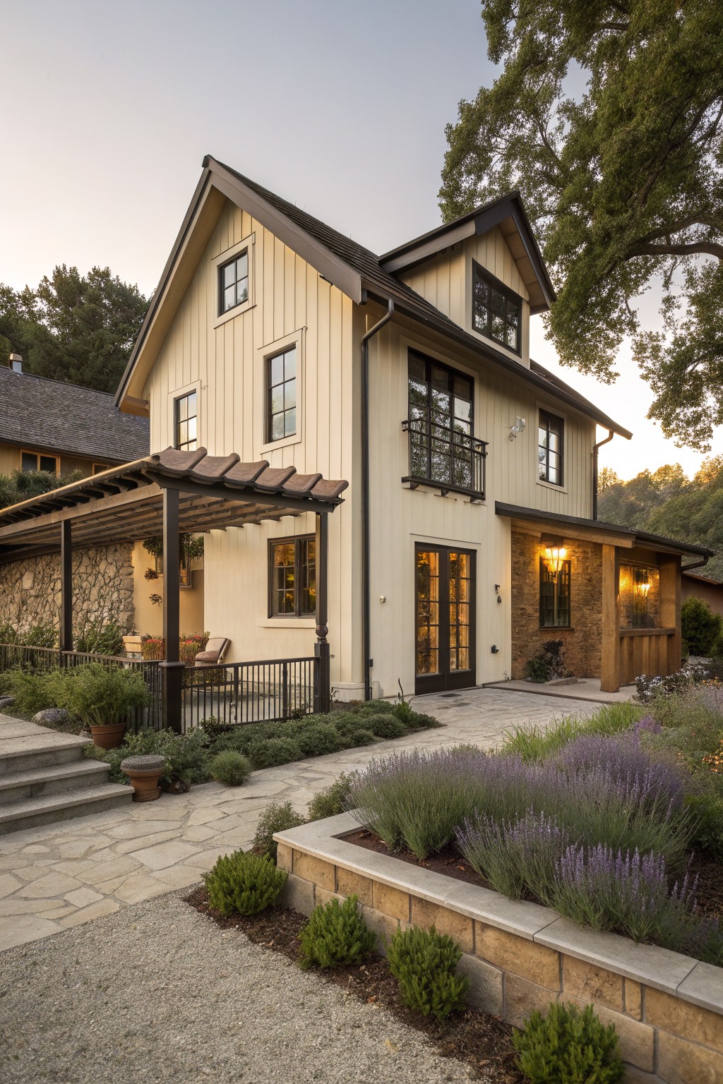 A two-story farmhouse exterior with pale yellow siding, dark trim on windows and doors, a covered entry, and stone landscaping in the foreground.