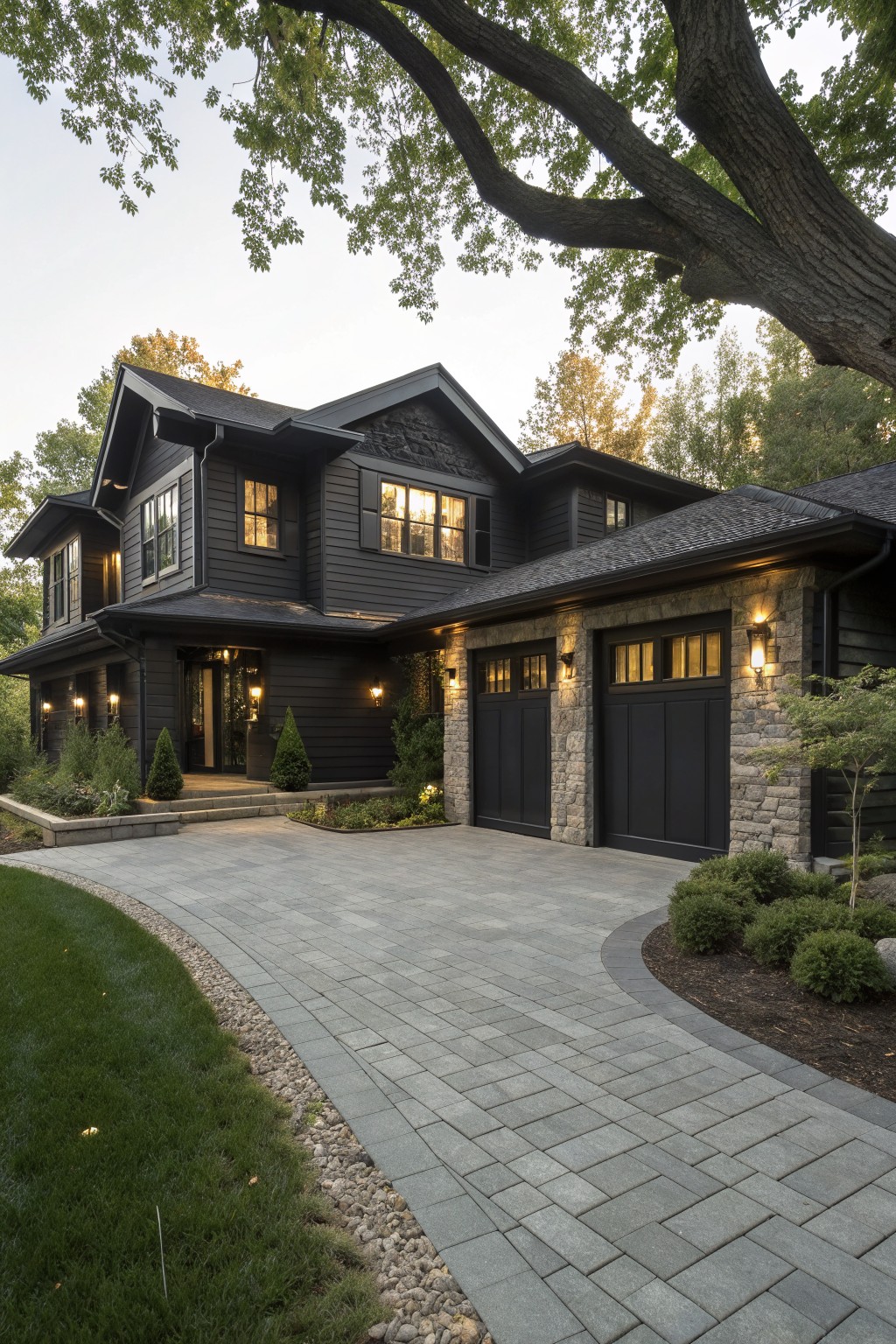 A two-story house with dark siding, stone accents on the garage walls, black garage doors, and a paved driveway curving in front.