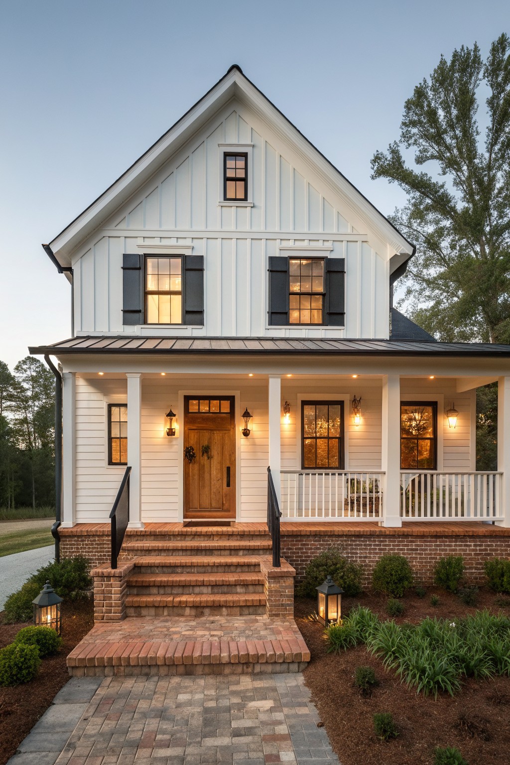 A two-story white farmhouse with black shutters, a wooden front door, brick foundation, and a covered porch with steps leading to a paved walkway.