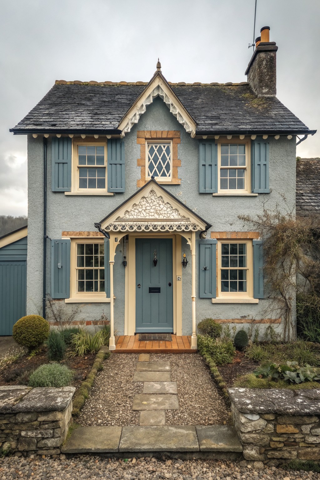 Blue-gray cottage with blue shutters, slate roof, and gravel path to door