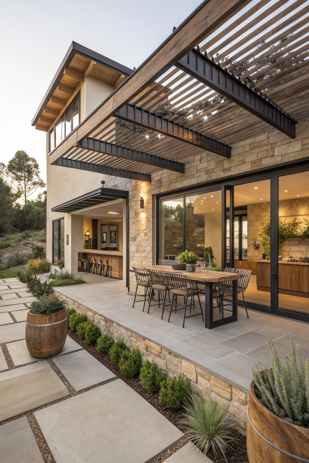 Modern stone house with patio dining table under wooden pergola and outdoor bar.