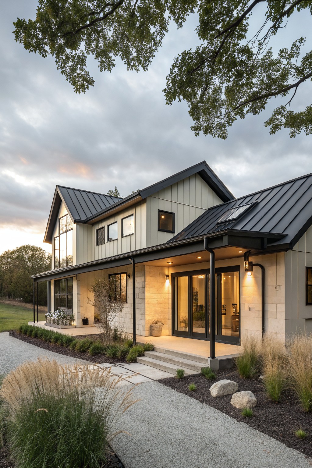 A two-story farmhouse exterior with light green vertical siding, a black metal gabled roof, black window and door trim, and a covered stone entry porch.
