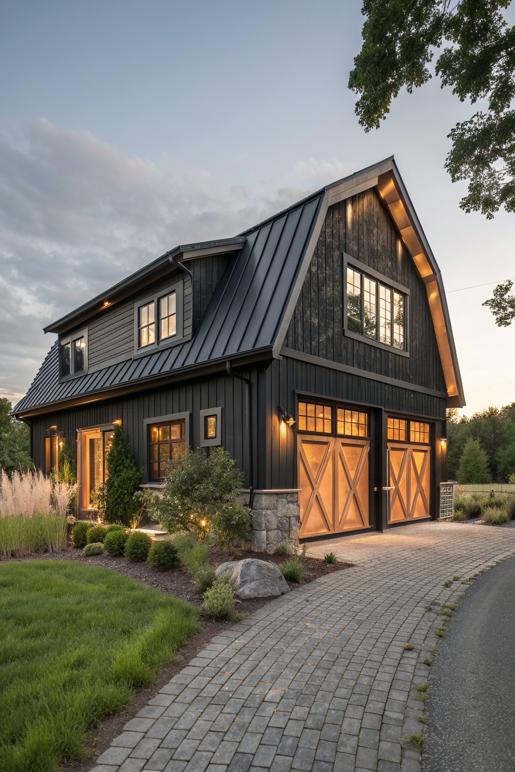 Modern black farmhouse exterior with wood garage doors, stone foundation, and paved driveway at dusk.