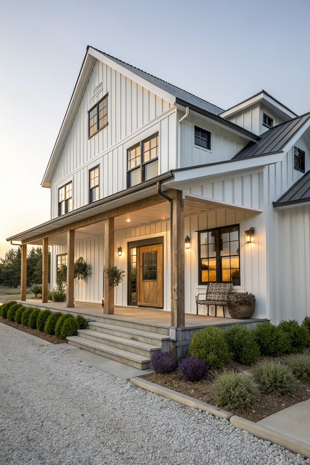 A two-story white farmhouse exterior with vertical siding, a covered wooden porch, black metal roof sections, and a centered wooden front door.