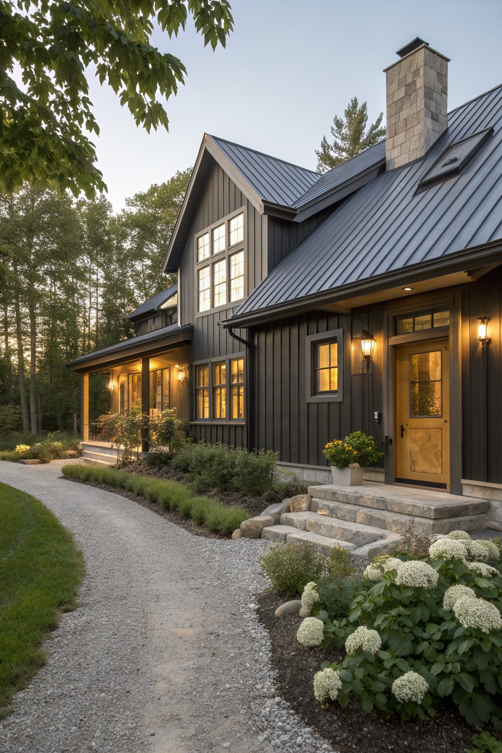 A modern farmhouse exterior with dark vertical siding, metal roof, stone chimney, and a light wood front door beside stone steps.