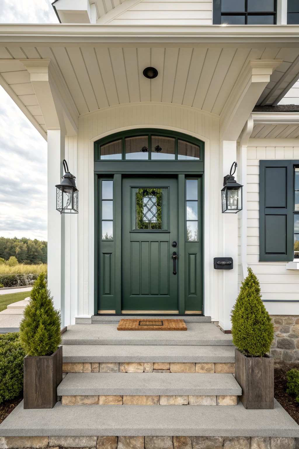 Dark green door with arched transom and sidelights on white porch with steps