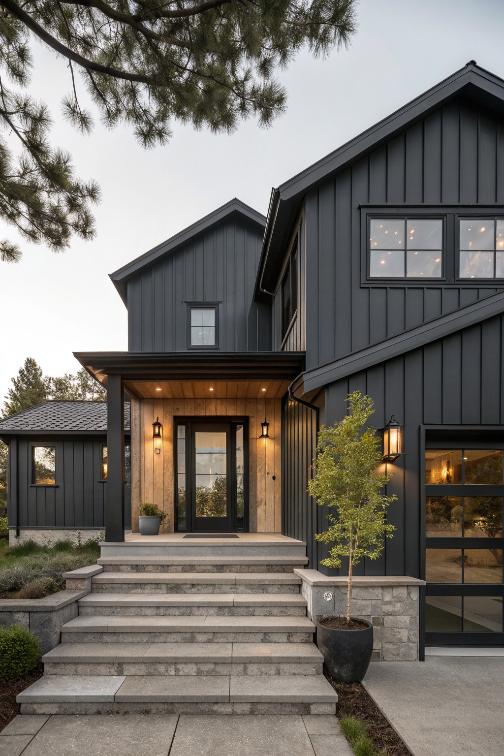 A dark gray modern farmhouse exterior with vertical siding, a wooden porch ceiling, black-framed windows, and concrete steps leading to a glass front door.