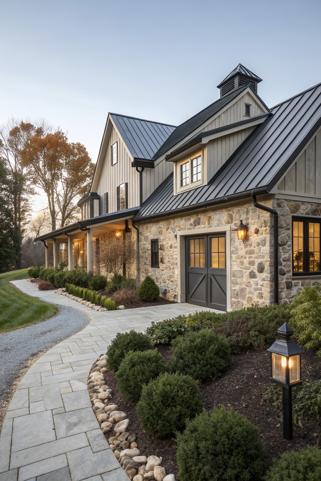Modern farmhouse with stone walls, gray siding, dark roof, and landscaped driveway.