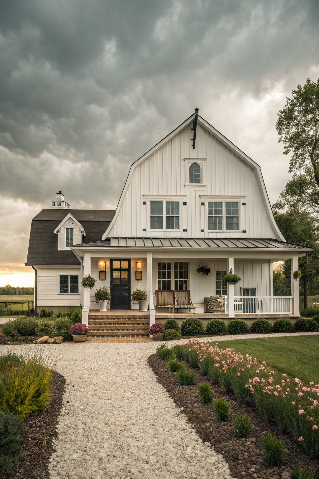 A white two-story farmhouse with a large front gable holding multiple oversized windows above a covered porch with steps and potted plants.
