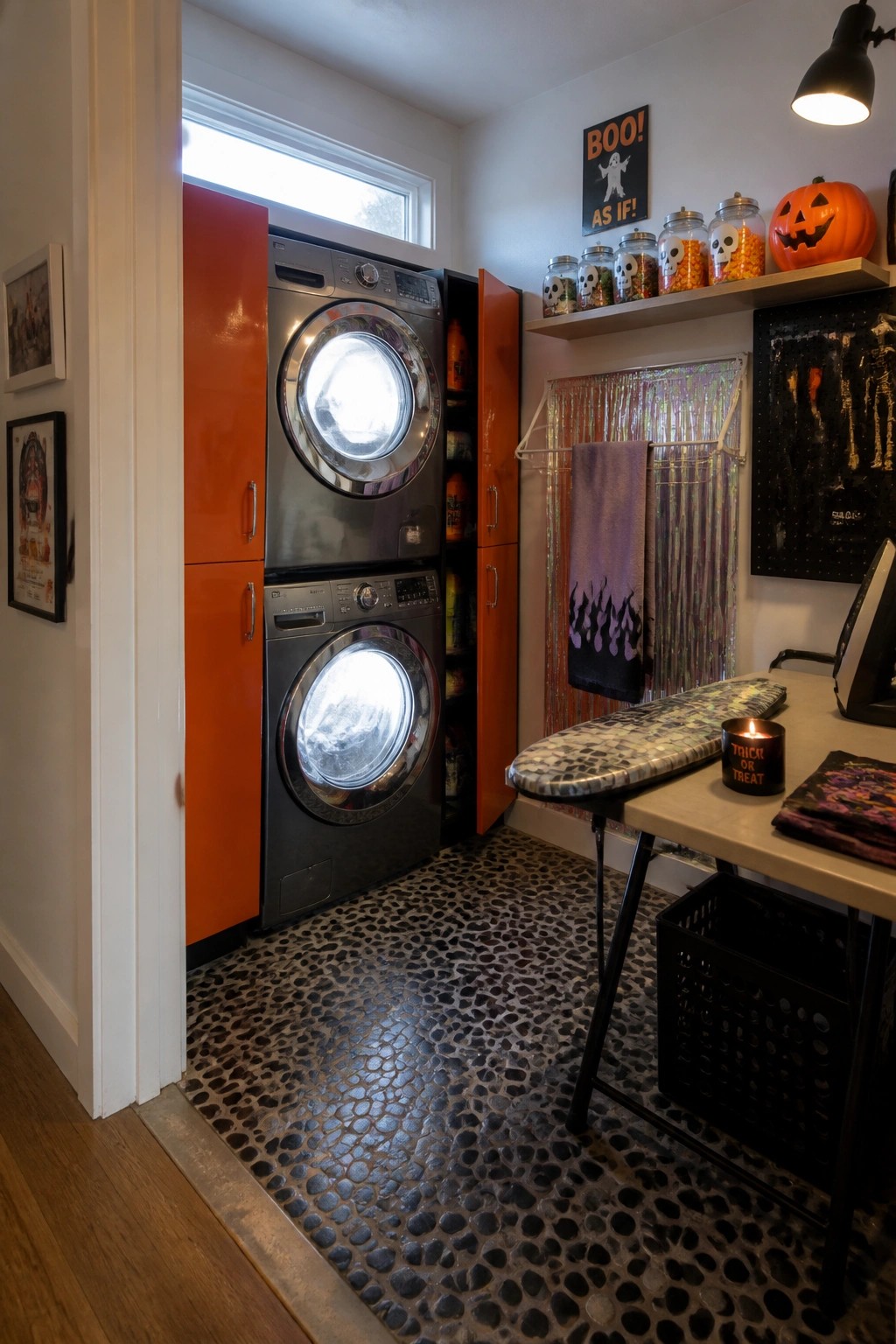 Stacked washer and dryer in orange cabinets on pebble floor with Halloween decor.