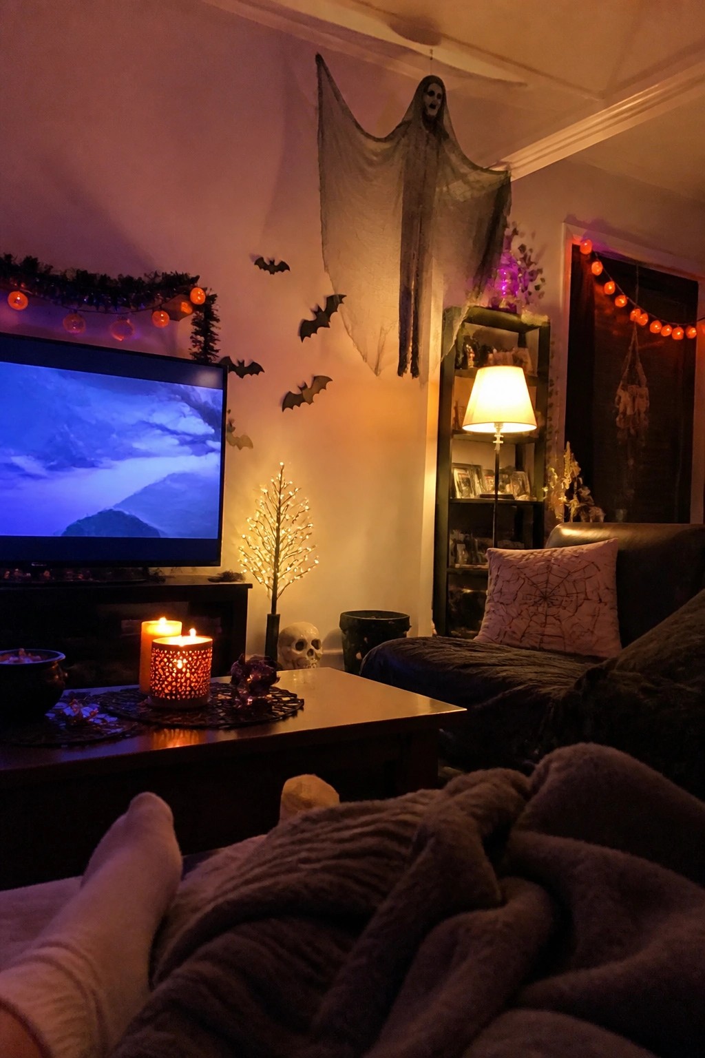 Living room wall decorated with a large hanging ghost figure and scattered black bats above a TV and coffee table.